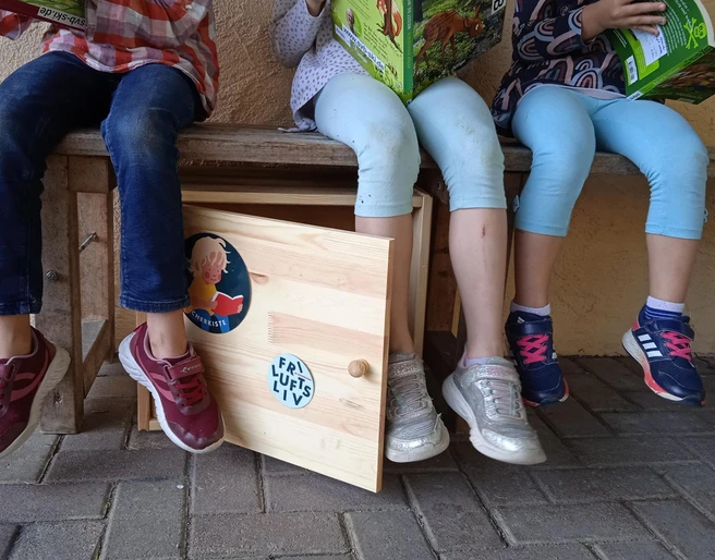 Kinder schauen sich Bücher aus der Bücherkiste an.