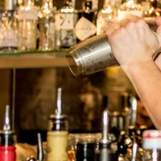 Bar Ein Barkeeper schüttelt einen Edelstahl-Shaker, im Hintergrund sind Flaschen zu sehen.A bartender shakes a stainless steel shaker, bottles can be seen in the background.