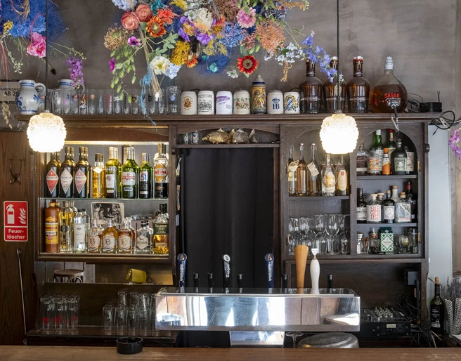 Forelle Blau Barbereich mit farbenfrohem Blumenschmuck und diversen Getränken; warmes und einladendes Ambiente.Bar area with colorful floral decorations and various drinks; warm and inviting ambience.