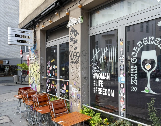 Zum Goldenen Schuss Kneipe mit Graffiti-verzierten Fenstern, die moderne urbane Kultur widerspiegeln.Pub with graffiti-decorated windows that reflect modern urban culture.