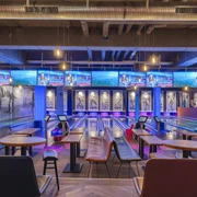 Bowling Bahnen im Underlux Interieur des Underlux Bowlingcenters mit blauen und violetten Lichtern, Tische im Vordergrund.Interior of the Underlux bowling center with blue and purple lights, tables in the foreground.