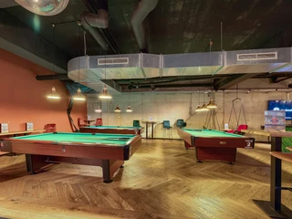 Billiard area in the Underlux Zwei Billardtische mit grünen Filz stehen in einem Raum mit hölzernem Fischgrätboden.Two billiard tables with green cloths stand in a room with a wooden herringbone floor.