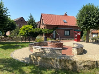 Eierbratstelle Winzlar Roter Klinkerbau im Hintergrund mit einem kleinen Backsteingrillplatz und Bänken im Vordergrund.
