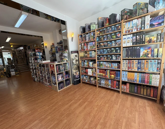 Brave New World entrance area Ein lichtdurchfluteter Raum voller Gesellschaftsspiele, die in hohen Regalen perfekt zur Schau gestellt sind.A light-flooded room full of board games, perfectly displayed on high shelves.
