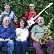 5 Real Book Combo.jpg Fünf Musiker mit Instrumenten sitzen und stehen lachend im Grünen, Bandname Real Book Combo.