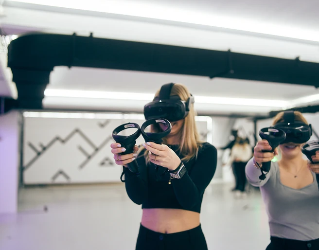 7th Space Cologne Zwei Personen stehen in einem hellen Raum und tragen VR-Headsets und Controller.Two people are standing in a bright room wearing VR headsets and controllers.