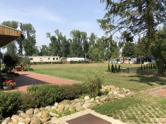 Naturcampingplatz "Im Braucke" mit großzügiger Wiese, angrenzenden Bäumen und Wohnwagen-Stellplätzen.