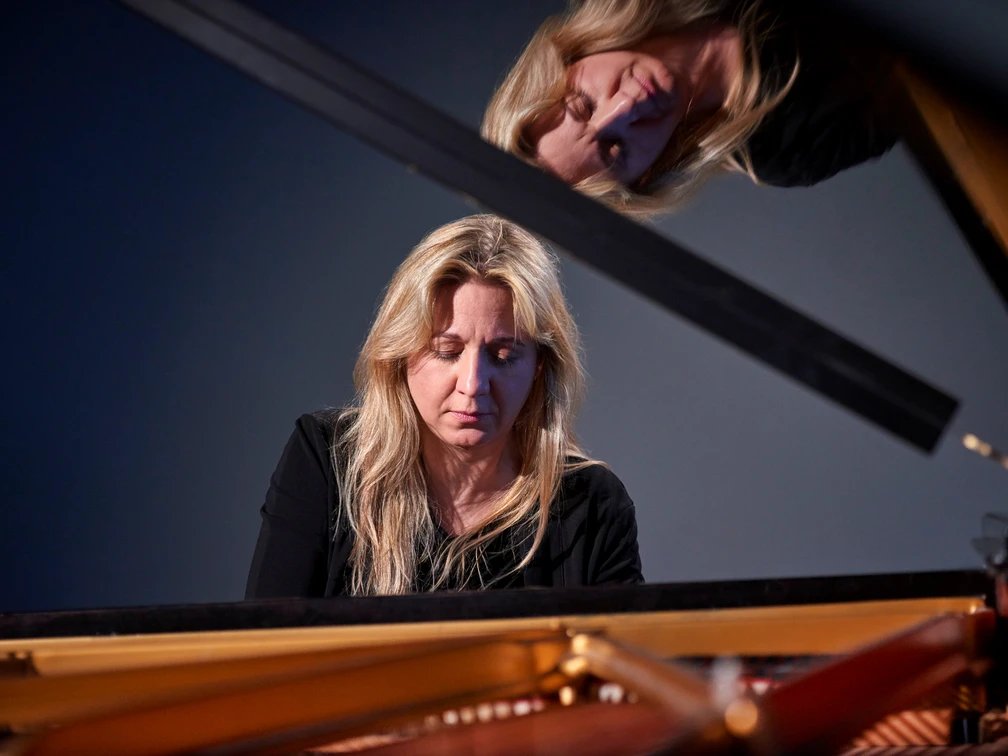 Ragna Schirmer Die Pianistin Ragna Schirmer vertieft am Flügel, mit einem reflektierenden Spiegelbild darüber.