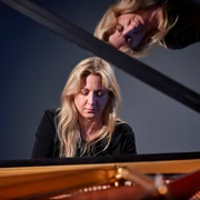 Ragna Schirmer Die Pianistin Ragna Schirmer vertieft am Flügel, mit einem reflektierenden Spiegelbild darüber.