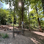 Niedrigseilgarten in Heiligenhaus Niedrigseilgarten in Heiligenhaus mit hölzernen Kletterelementen, umgeben von Bäumen und Sonnenlicht.