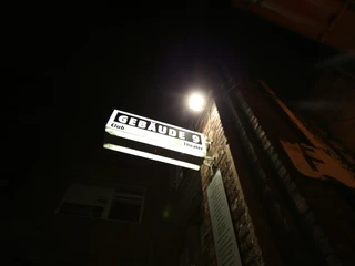 Gebäude 9 Gebäude 9 leuchtet durch ein markantes Schild bei Nacht, mit Graffiti an der Klinkerfassade.Building 9 is illuminated by a striking sign at night, with graffiti on the brick façade.