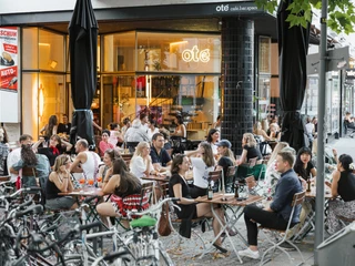 Oté Eine Menschenmenge genießt Getränke im Freien vor einem Café mit großen Fenstern in Köln.A crowd enjoys drinks outside a café with large windows in Cologne.