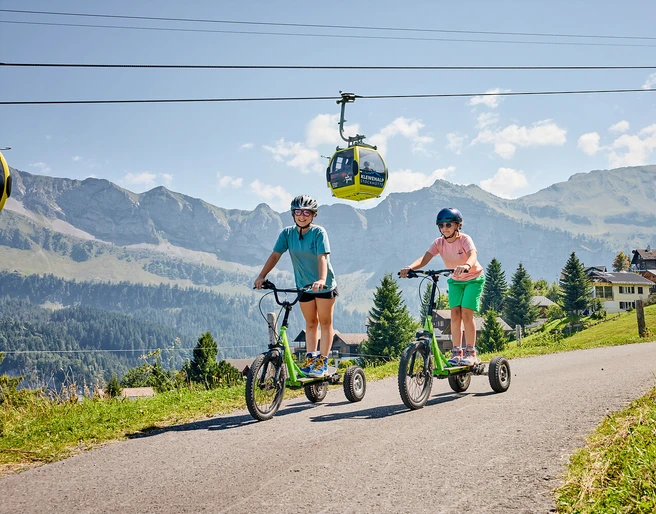 Bikeboard-Stockhütte (5).jpg Zwei Mädchen am Bikeboard fahren auf der Stockhütte.