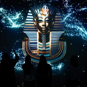 Tutankhamun - His Tomb and His Treasures Die beeindruckende Maske des Tutanchamun leuchtet eindrucksvoll vor dunklem Hintergrund.The impressive mask of Tutankhamun glows impressively against a dark background.