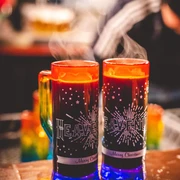 Glühwein - HEAVENUE Cologne Zwei dampfende Glühweintassen mit "HEAVENUE", die in festlicher Stimmung leuchten.Two steaming cups of mulled wine with "HEAVENUE", glowing in a festive atmosphere.