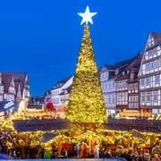 Weihnachtsmarkt Celle  Weihnachtsmarkt in Celle: Leuchtender Tannenbaum, umgeben von Fachwerkhäusern und Menschenmenge.