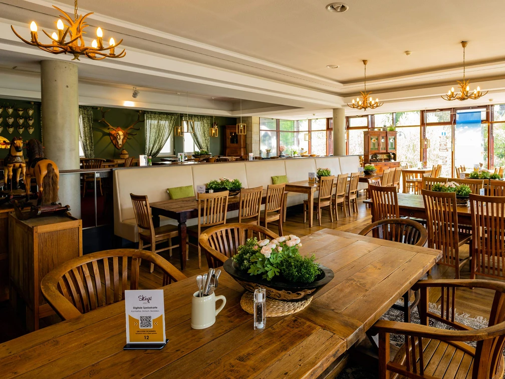 Panorama Bistro im Hotel Rathener Hof Einladende Bistro-Atmosphäre mit Holzmöbeln, eleganter Beleuchtung und einem Blick auf üppige Natur.