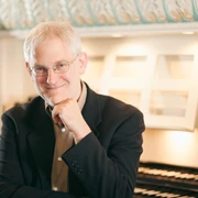 Jan Katzschke ORGEL Fotograf Sebastian Kaulfürst.jpg Porträt von Jan Katzschke in eleganter Kleidung vor einer Orgelkulisse, freundlich lächelnd.