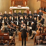 KammerchorMariensee.JPG Ein Chor singt in einem historischen Kirchensaal, umgeben von Zuschauern und Musikern mit Instrumenten.