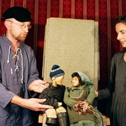 figurentheater-ernst-heiter-vom-fischer-und-seiner-frau.jpg Zwei Personen führen Holzpuppen im Märchen „Vom Fischer und seiner Frau“ vor rotem Bühnenhintergrund.
