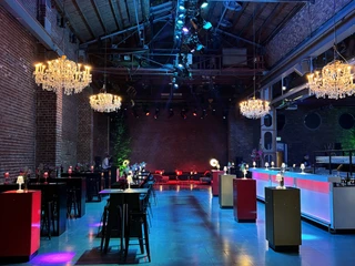 BALLONI Halle_11 Halle mit hohen Decken, Backsteinwänden, Kronleuchtern und bunter Beleuchtung für Veranstaltungen.Hall with high ceilings, brick walls, chandeliers and colorful lighting for events.