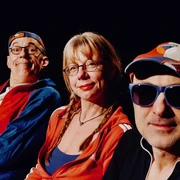 251203_JStaidelCombo.jpg Drei Personen in sportlicher Kleidung und Sonnenbrillen blicken lächelnd in die Kamera vor schwarzem Hintergrund.