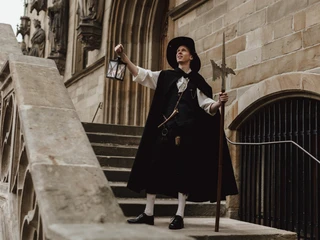 Nachtwächter (2).jpg Eine Nachtwächterin führt mit Laterne und Hellebarde geschichtsbewusste Besucher über eine Steintreppe.A night watchman with a lantern and halberd guides history-conscious visitors up a stone staircase.Een nachtwaker met lantaarn en hellebaard leidt geschiedenisbewuste bezoekers een stenen trap op.