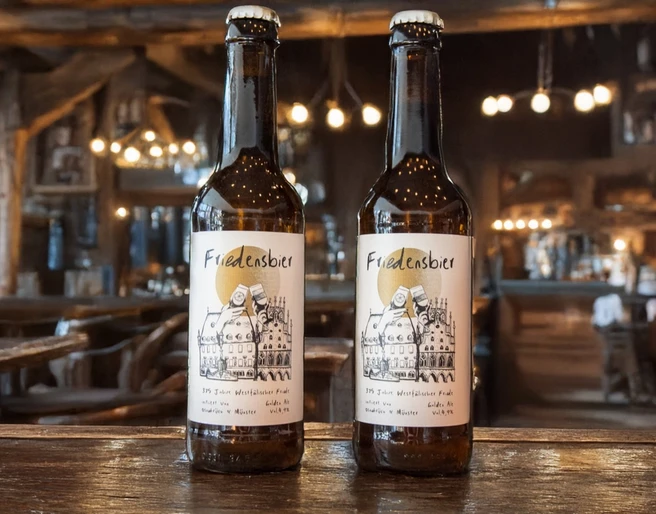 Beschwipster Nachtwächter (Hauptbild).jpg Zwei Flaschen Friedelnsbier stehen in einem rustikalen Wirtshaus mit stimmungsvoller Beleuchtung.