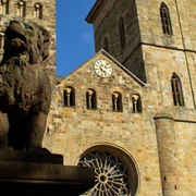 Altstadt-Highlights (Hauptbild).jpg Steinerne Skulptur eines Löwen vor einer historischen Kirche mit zwei Türmen und einer großen Uhr.Stone sculpture of a lion in front of a historic church with two towers and a large clock.Stenen beeld van een leeuw voor een historische kerk met twee torens en een grote klok.