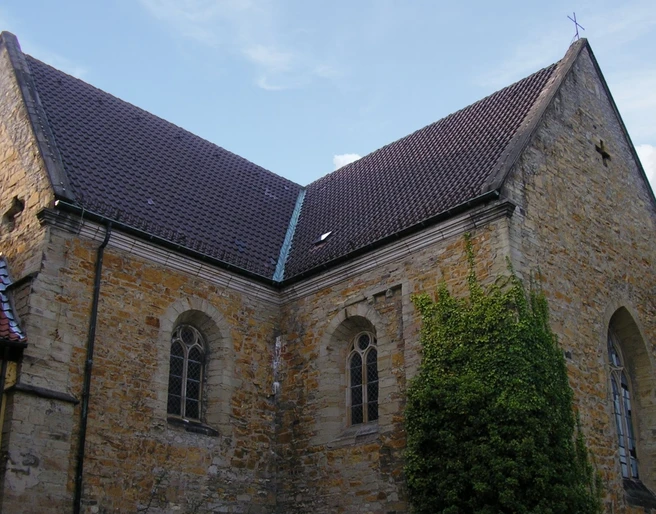 Gertrudenberg (Hauptbild).jpg Historische Kirchenmauer aus Backstein, flankiert von Fenstern mit gotischem Stil, bewachsen mit Efeu.Historic brick church wall, flanked by Gothic-style windows, overgrown with ivy.Historische bakstenen kerkmuur, geflankeerd door ramen in gotische stijl, overwoekerd door klimop.