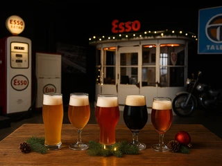 ChatGPT Image 12. Aug. 2025, 00_21_11.png Fünf Biergläser auf Tisch, Hintergrund zeigt alte Esso-Tankstelle mit Weihnachtsdekoration.Five beer glasses on table, background shows old Esso gas station with Christmas decorations.