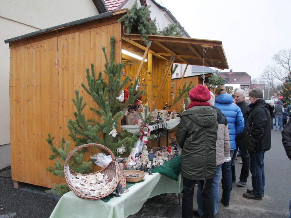 Weihnachtsmarkt Beucha - Weihnachten in der Region Leipzig Festlich geschmückter Weihnachtsmarktstand mit handgefertigten Waren, vor dem sich Besucher umschauen und stöbern