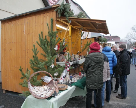 Weihnachtsmarkt Beucha - Weihnachten in der Region Leipzig Festlich geschmückter Weihnachtsmarktstand mit handgefertigten Waren, vor dem sich Besucher umschauen und stöbern