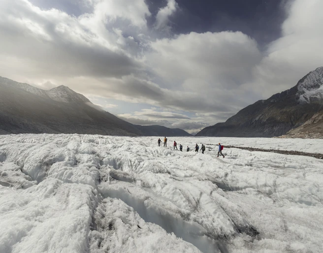 Gruppe auf dem Gletscher unterwegs Teilnehmer der UNESCO Gletschertour Aletsch bewegen sich in Seilschaft über die weiten Eisfelder des Aletschgletschers