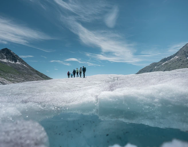 Wanderer auf Aletschgletscher im Sommer Gruppe von Wanderern überquert den Aletschgletscher an einem klaren Sommertag während der 2-Tage-Erlebnis Gletschertour AletschGroup of hikers cross the Aletsch Glacier on a clear summer day during the 2-day Aletsch Glacier Tour experienceGroupe de randonneurs traversant le glacier d'Aletsch par une claire journée d'été lors du tour du glacier d'Aletsch de 2 jours.