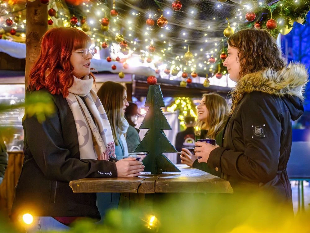 Vier junge Frauen beim Glühweintrinken in weihnachtlicher Atmosphäre auf dem Acherner Weihnachtsmarkt