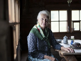 Témoin de la tradition alpine au musée de l'alpage Schaubuttern Alpmuseum Aletsch mit einer Frau in traditioneller Kleidung am Holztisch in der AlphütteAletsch Alpine Museum show chute with a woman in traditional dress at the wooden table in the Alpine hutSchaubuttern Alpmuseum Aletsch avec une femme en habits traditionnels à la table en bois dans le chalet d'alpage