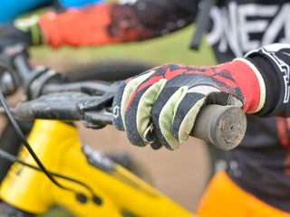 Detailaufnahme Bikehandschuh am Lenker Kinderbikekurs Riederalp mit Nahaufnahme eines Handschuhs am Lenker eines gelben Mountainbikes