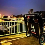 RikoloniaWinterTeamlicht.png Ein winterlich beleuchtetes Rikscha-Team vor dem Kölner Rheinpanorama bei Abenddämmerung.A wintery illuminated rickshaw team in front of the Cologne Rhine panorama at dusk.