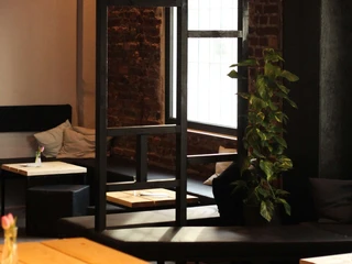 Der schwarze Hase Ein stilvolles Interieur mit Ziegelwänden, einer Sprossenfensterfront und einem Efeu.A stylish interior with brick walls, a mullioned window front and ivy.