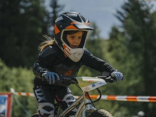 Young biker on the Bettmeralp children's bike course Kinderbikekurs Bettmeralp mit Nahaufnahme einer jungen Bikerin in voller Schutzausrüstung beim FahrenChildren's bike course Bettmeralp with close-up of a young biker in full protective gear ridingCours de VTT pour enfants à Bettmeralp avec gros plan sur une jeune vététiste en train de rouler avec son équipement de protection complet