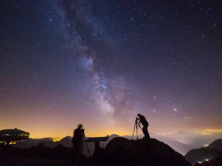 Astrofotografen unter der Milchstrasse Sternenfotografie Bettmerhorn zeigt zwei Fotografen mit Stativen unter der leuchtenden Milchstrasse hoch über der Aletsch Arena