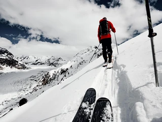Skitour oberhalb des Aletschgletschers Aletschgletscher Rundtour Ski mit Skitourengeher auf verschneitem Grat oberhalb des Gletschers, Aufstieg bei Wolken und Sonne