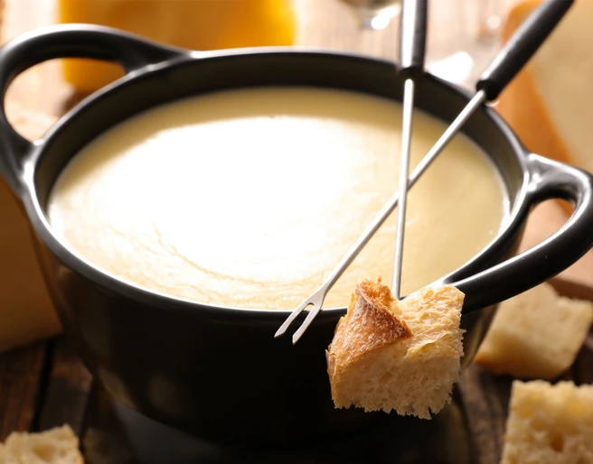 Klassisches Schweizer Käsefondue Fondue oder Racletteplausch Aletsch Arena mit traditionellem Schweizer Käsefondue und Brotstücken im Restaurant Chüestall Riederalp