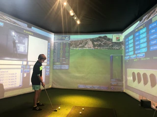 Entraînement de golf en salle pour les enfants Indoor Golf Bettmeralp im Sportzentrum Bachtla mit Kind am Golfsimulator beim Training auf virtueller Driving RangeIndoor Golf Bettmeralp at the Bachtla sports center with a child on the golf simulator while training on the virtual driving rangeIndoor Golf Bettmeralp au centre sportif Bachtla avec un enfant sur le simulateur de golf lors de l'entraînement sur le driving range virtuel