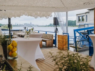 IMG_4665.JPG Hochzeitslocation mit Wasserblick, dekoriert mit Luftballons und weißen Stehtischen.Wedding location with a view of the water, decorated with balloons and white bar tables.