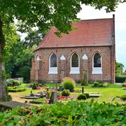 Kapelle Vreschen-Bokel Die Kapelle in Vreschen-Bokel aus Backstein mit roten Dachziegeln, umgeben von gepflegten Gräbern und Pflanzen.