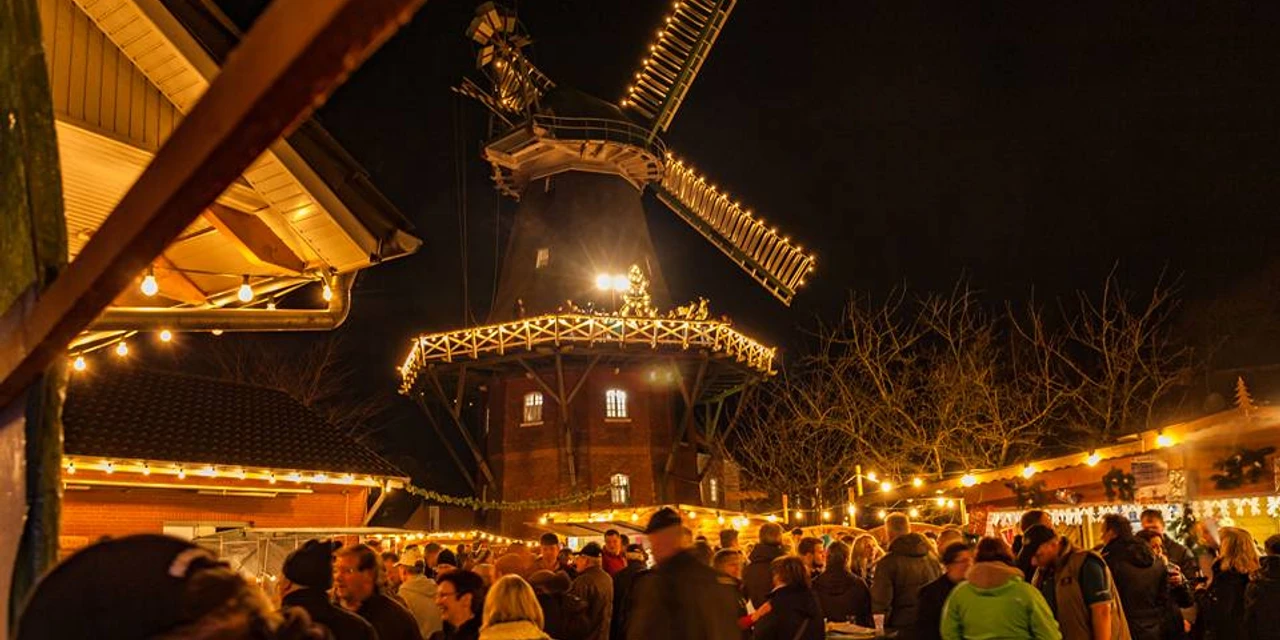 Weihnachtsmarkt-Wiegboldsbur.jpg viele Menschen auf einen Platz vor einer Windmühle, die beleuchtet ist