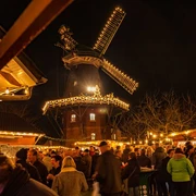 Weihnachtsmarkt-Wiegboldsbur.jpg viele Menschen auf einen Platz vor einer Windmühle, die beleuchtet ist