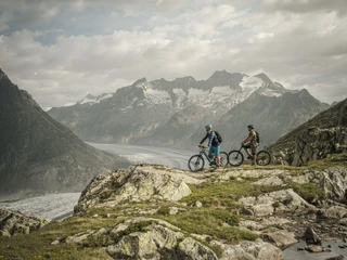 Faire du vélo avec vue sur le glacier d'Aletsch Bike Genuss Tour Aletsch Arena mit Bikern oberhalb des Grossen Aletschgletschers auf einer genussvollen Panoramastrecke im WallisBike pleasure tour Aletsch Arena with bikers above the Great Aletsch Glacier on an enjoyable panoramic route in ValaisBike Genuss Tour Aletsch Arena avec des vététistes au-dessus du grand glacier d'Aletsch sur un parcours panoramique savoureux en Valais
